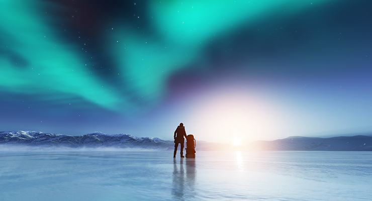 adventurous man standing with a backpack looking northern lights